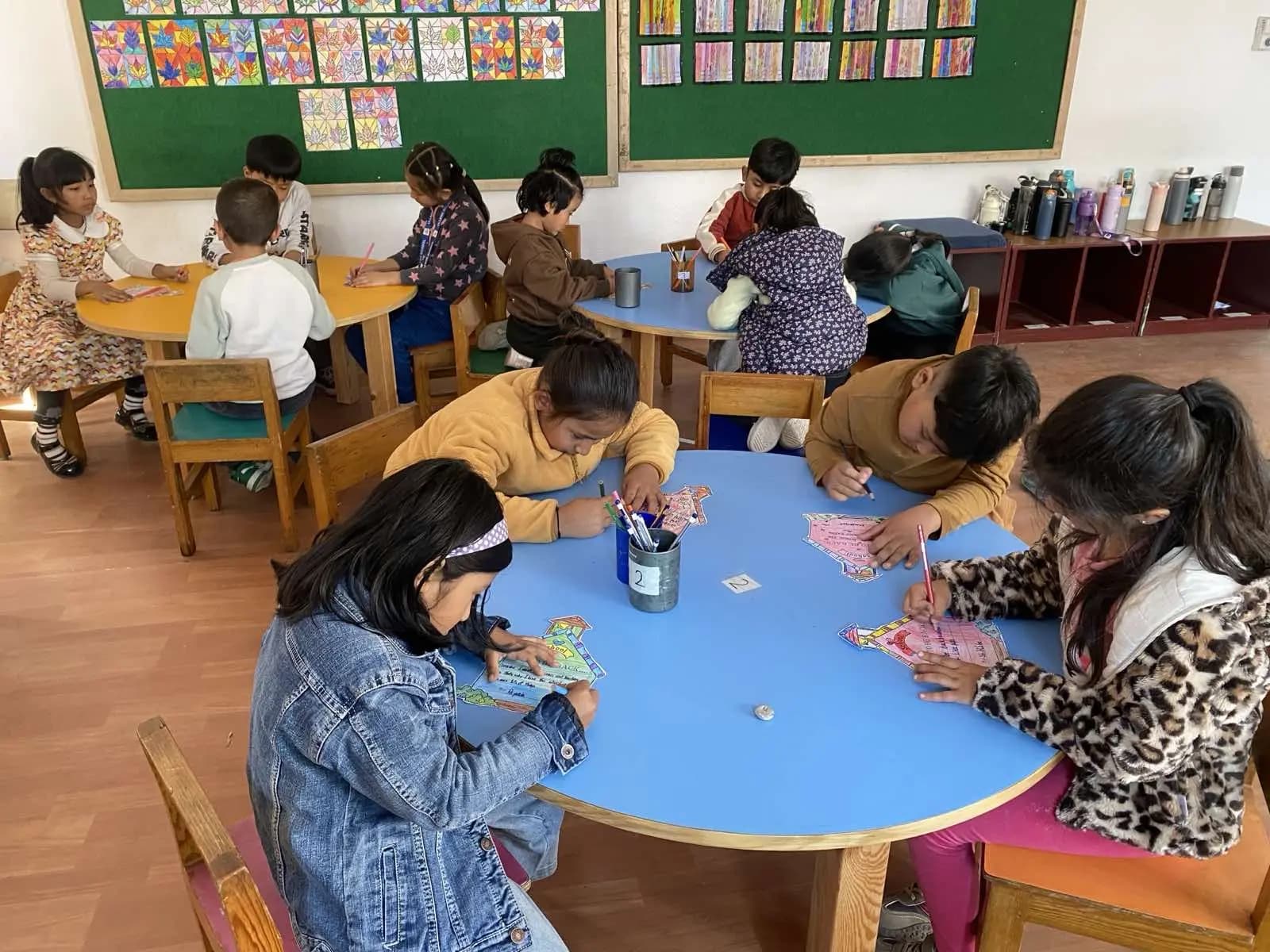 Children at round tables beside the bookshelves
