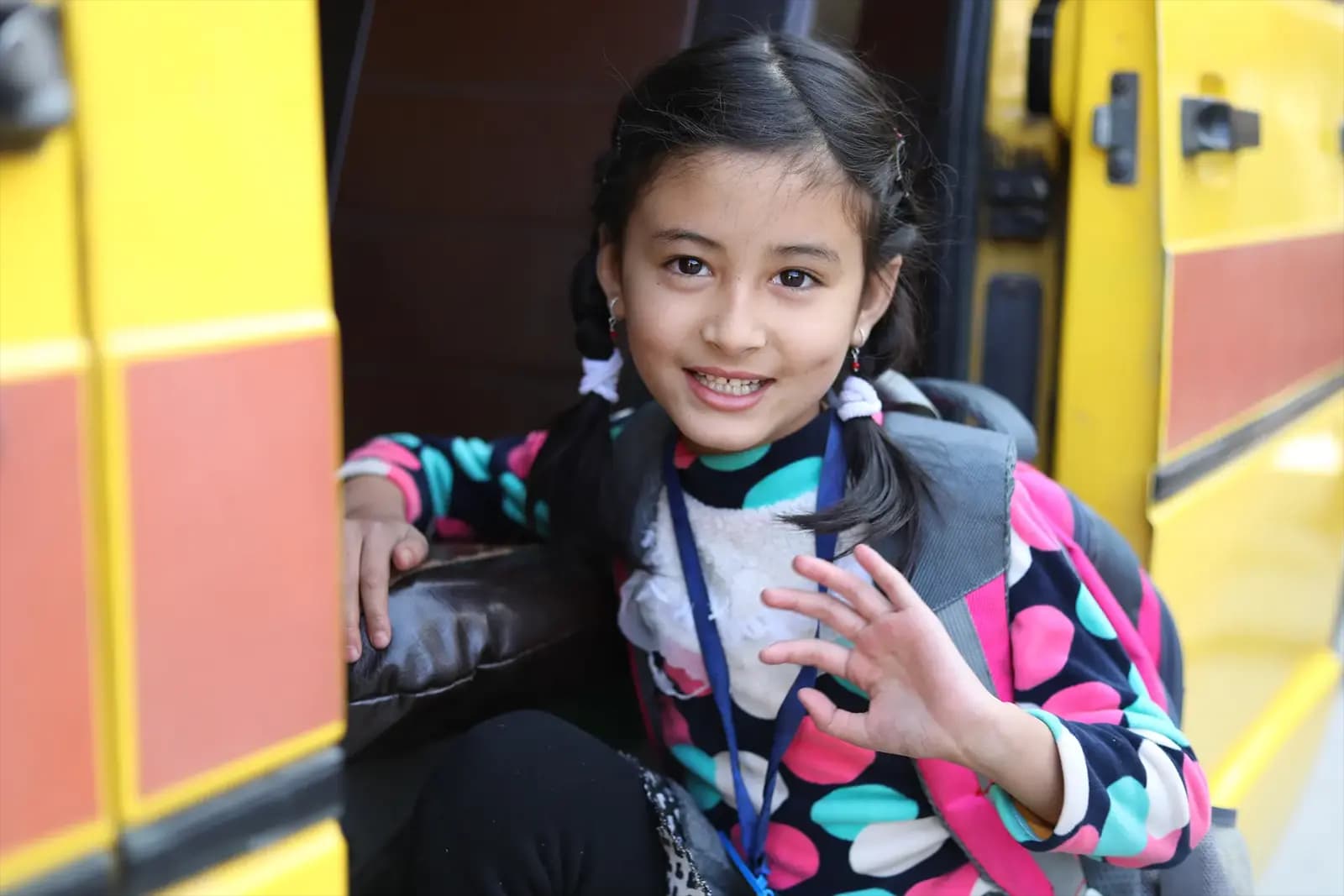 A child waving from the school van door
